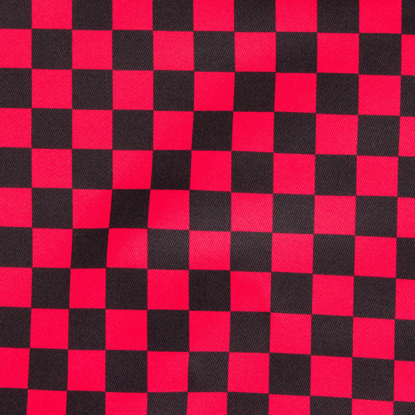 The Black & Viva Magenta Checkerboard Stretch Twill Fabric laid flat. The red and black checker print fabric is digitally printed and is stretch cotton.