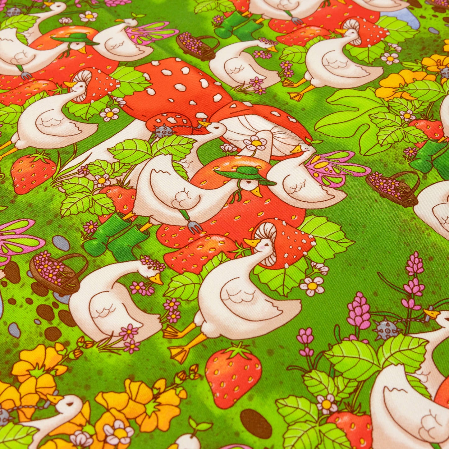 Close up of the In the Geese Garden Stretch Twill Fabric. The green base fabric features white geese amongst giant strawberries, mushrooms, pink, yellow and white flowers, and ponds. Inspired by gardening and cottagecore fashion the design features geese with mushroom hats, green wellies, flower crowns, frog hats, fairy wings and a medieval mace.