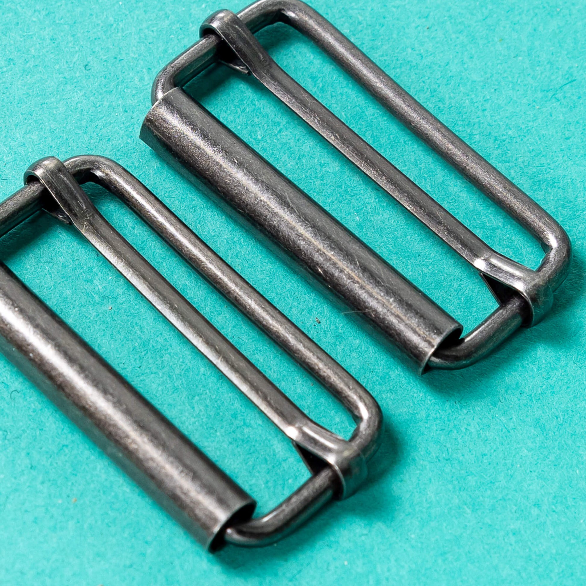 close up of silver buckle fastenings on a green background