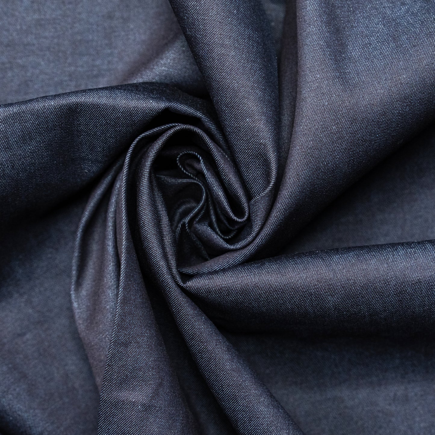 Indigo stretch denim fabric in a soft swirl to show flexibility and sheen, stocked by Brunswick Mills for clothing and craft projects.