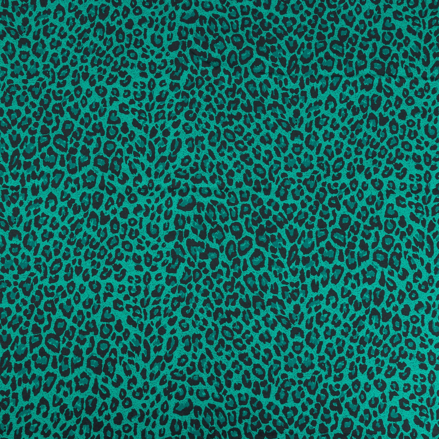 A wide shot of the green and black leopard print stretch jersey fabric for making clothing and craft projects