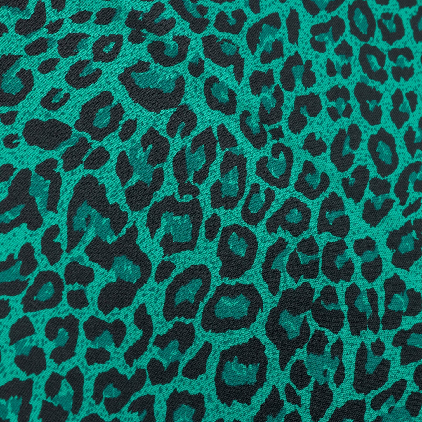 A close up shot of the green and black leopard print stretch jersey fabric for making clothing and craft projects
