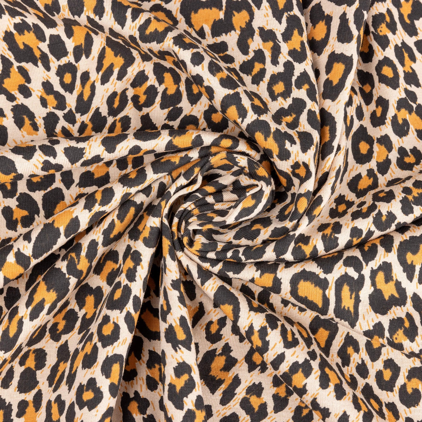 A swirl of the natural leopard print fabric with orange, beige and black to form the leopard spots on a sand background