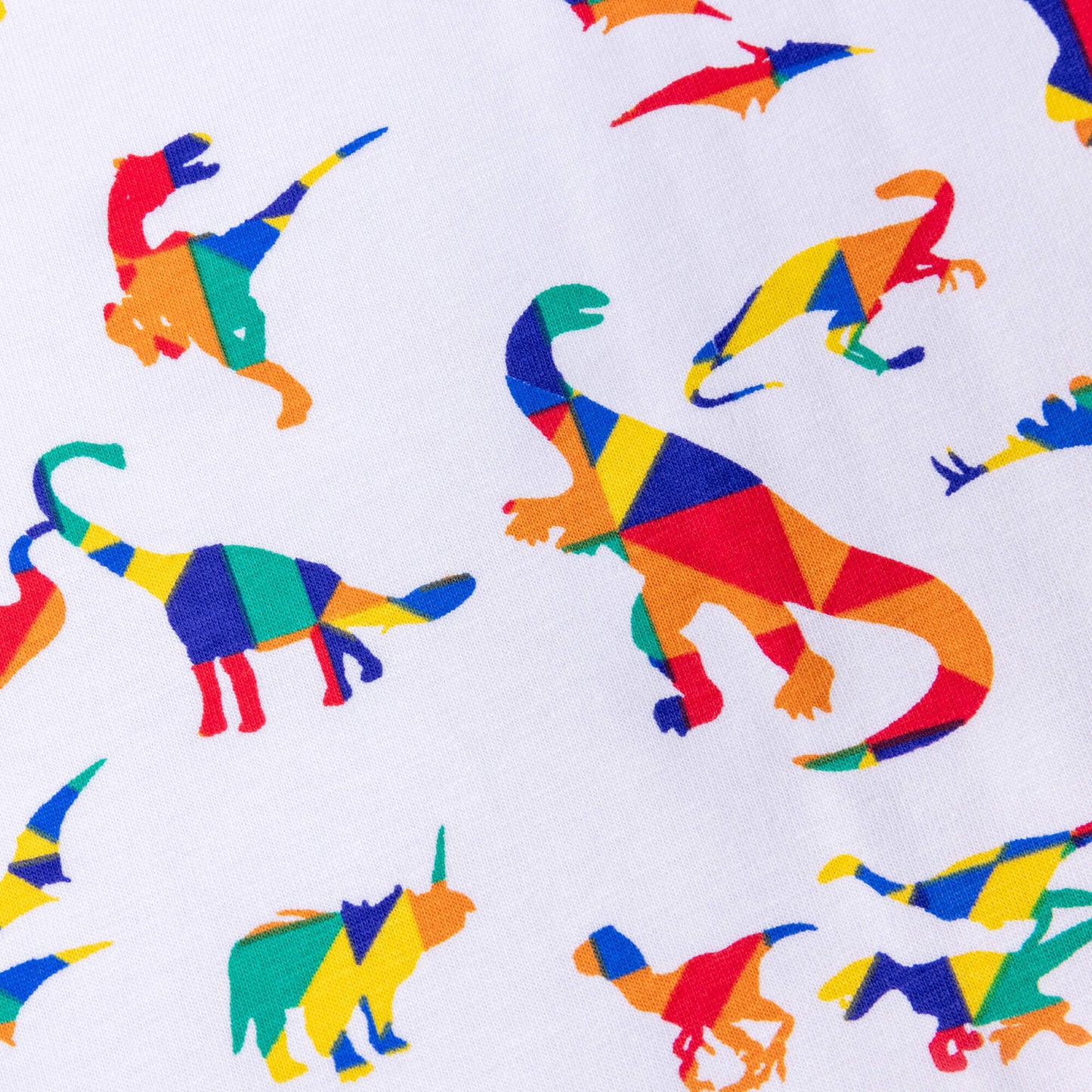 A close up look at the White Rainbow Dinosaur Stretch jersey fabric it has different dinosaurs on a white background the dinosaurs are in bold primary colours in a kaleidoscope style