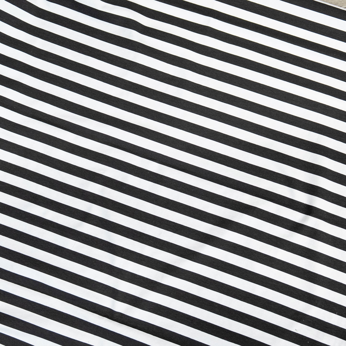Flatlay of black and white striped stretch jersey fabric with diagonal pattern, great for bold fashion projects and comfy garments.