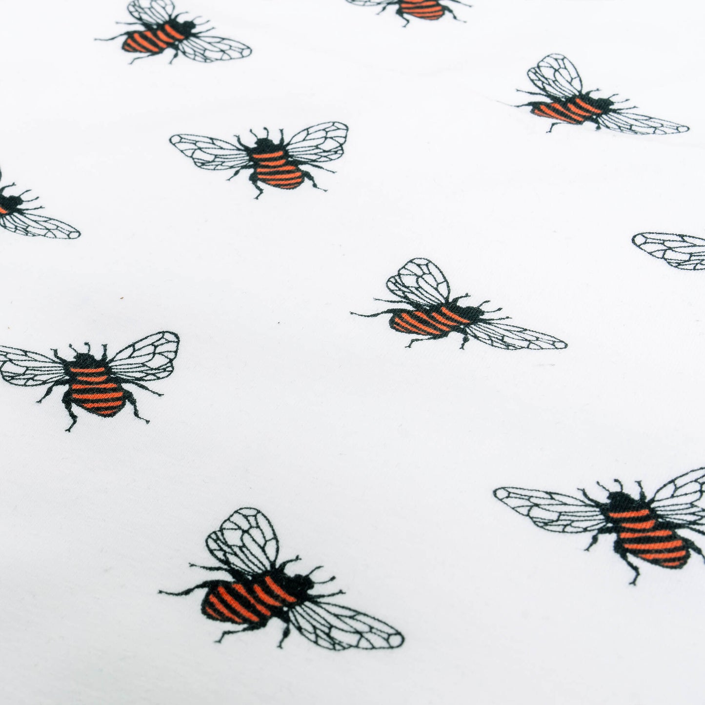 Close-up view of white fabric featuring a repeating pattern of bees. The bees are illustrated with black and orange striped bodies and delicate, transparent wings. The pattern is evenly spaced, showcasing the detailed design of each bee.