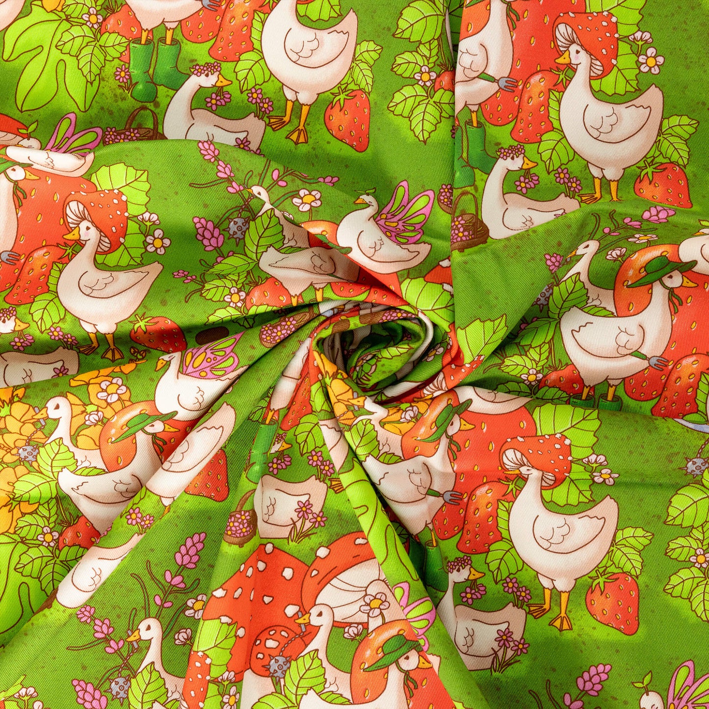 The In the Geese Garden Stretch Twill Fabric swirled folded in the centre. The green base fabric features white geese amongst giant strawberries, mushrooms, pink, yellow and white flowers, and ponds. Inspired by gardening and cottagecore fashion the design features geese with mushroom hats, green wellies, flower crowns, frog hats, fairy wings and a medieval mace.