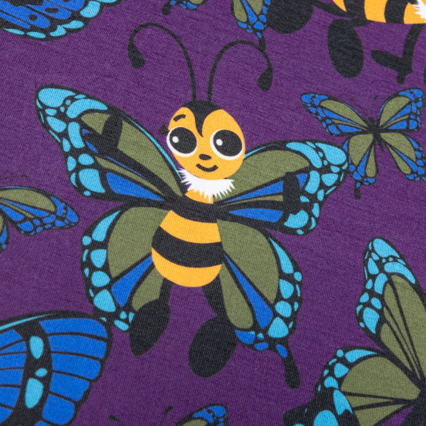 A close up of cute cartoon bees with butterfly wings. The bees are yellow and black with eyelashes, their wings are blue and green. They are against a purple background with various sized butterflies too.
