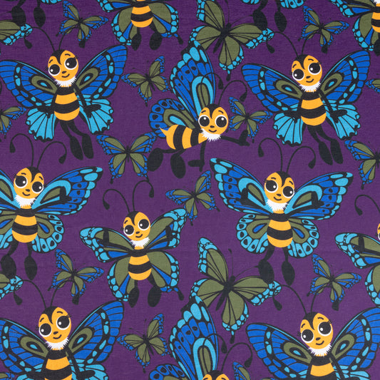 A fabric showing cute cartoon bees with butterfly wings. The bees are yellow and black with eyelashes, their wings are blue and green. They are against a purple background with various sized butterflies too.