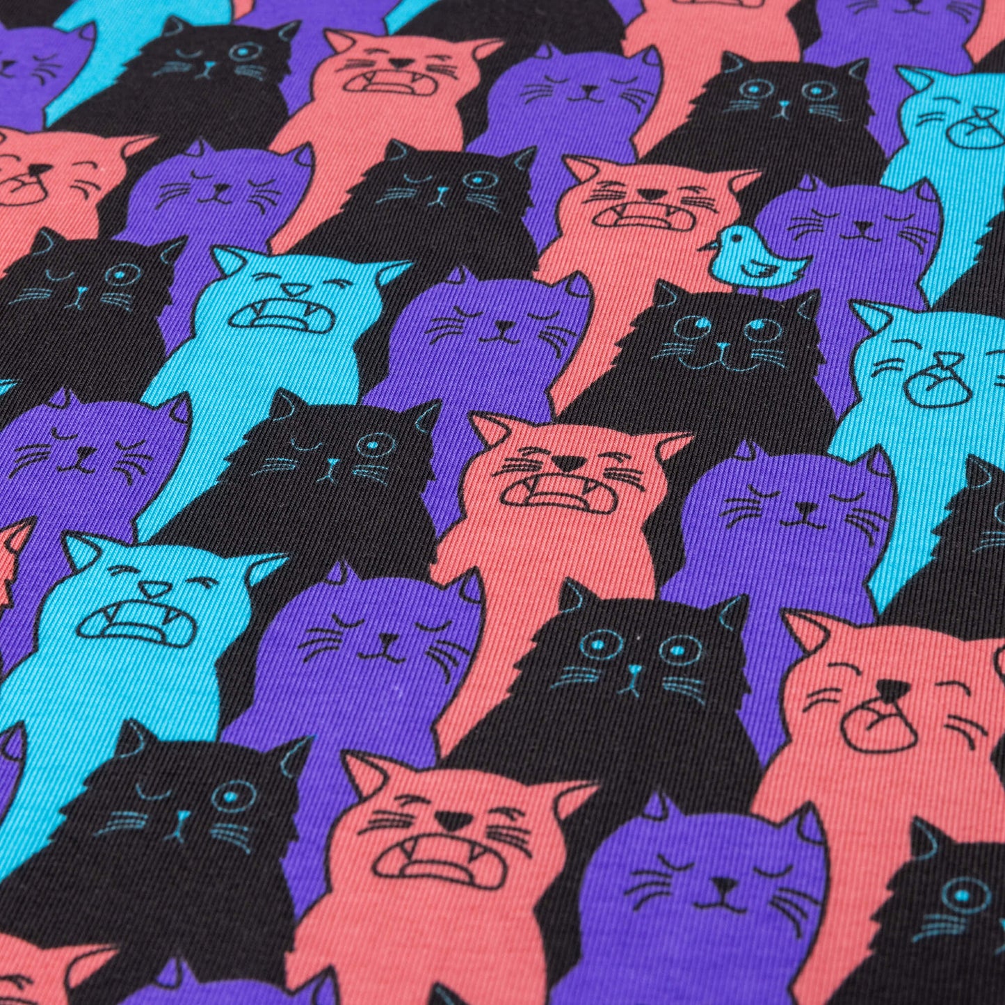 A stretch jersey fabric featuring cats that look like they are winking, singing or have their eyes shut, their is a bird one one of their heads. They are purple, black, pink and bright blue.
