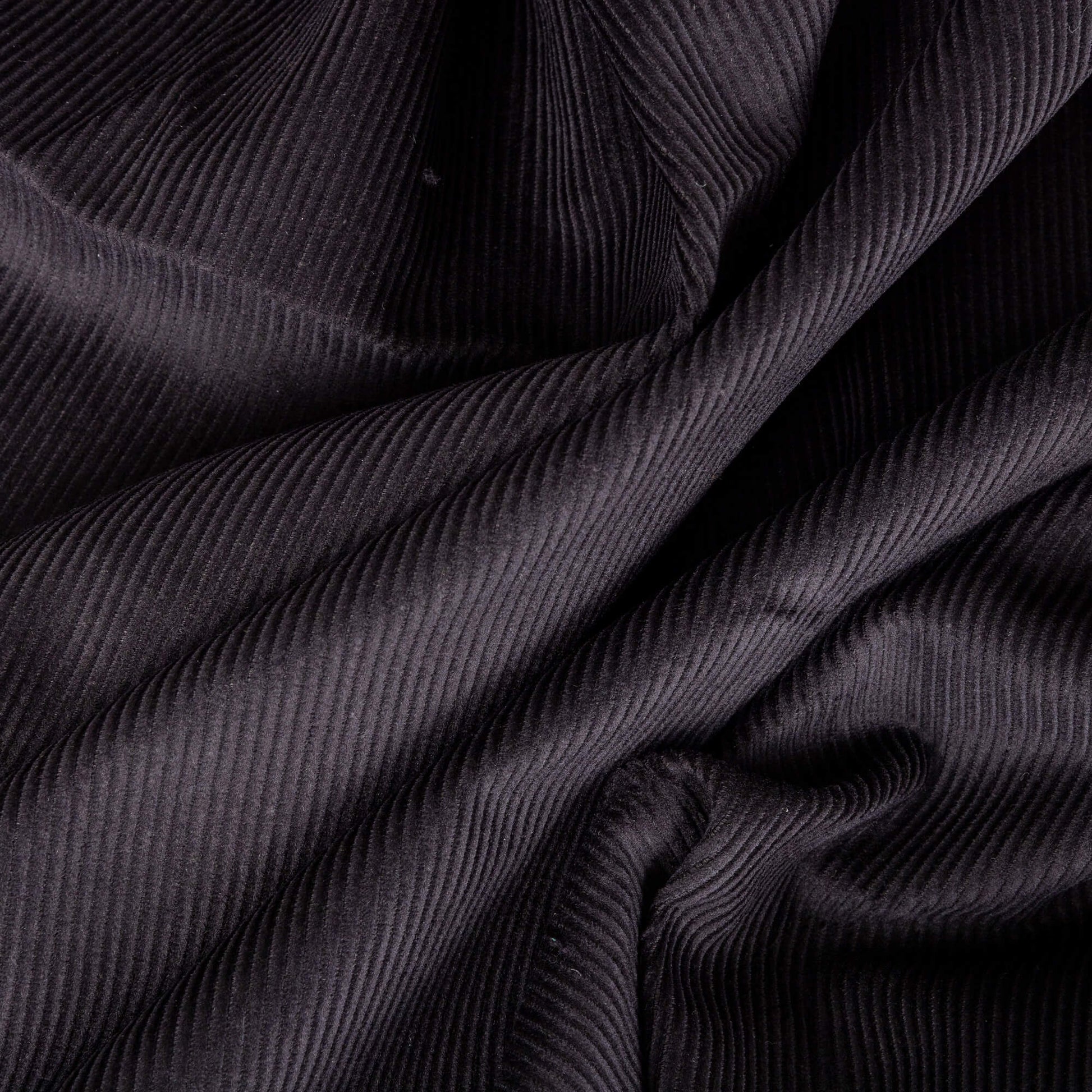 picture of black corduroy fabric, the cord fabric looks like it is in waves and is ready for craft projects 