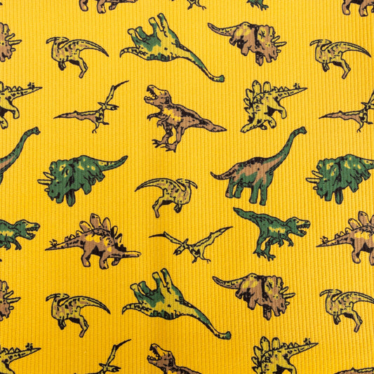 A close up of the stretch gold mustard coloured dinosaur corduroy fabric with different dinos great for children's clothing, sewing and homeware projects