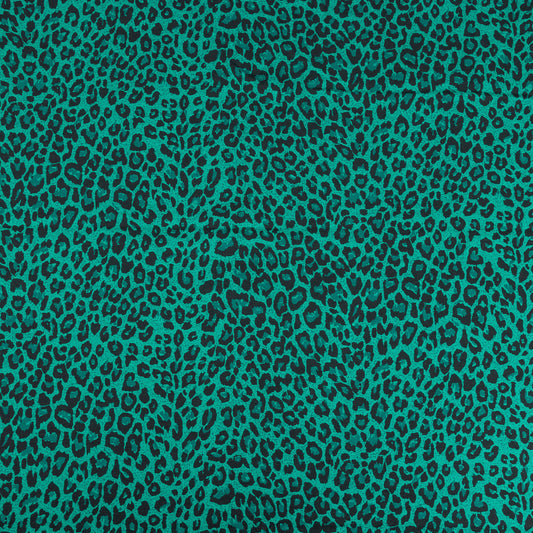 A wide shot of the green and black leopard print stretch jersey fabric for making clothing and craft projects 