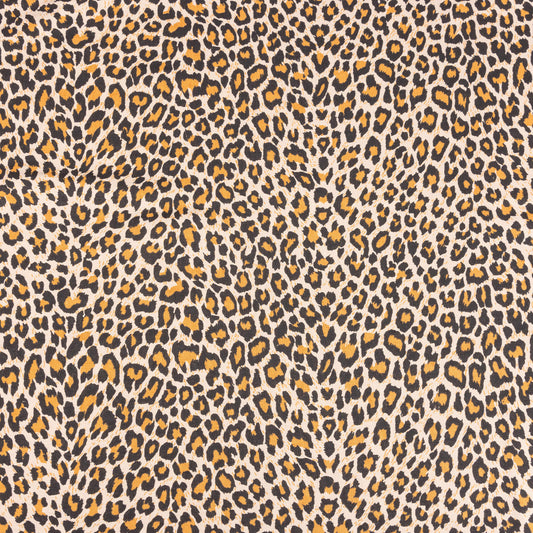 A wide look at the natural leopard print fabric with orange, beige and black to form the leopard spots on a sand background 