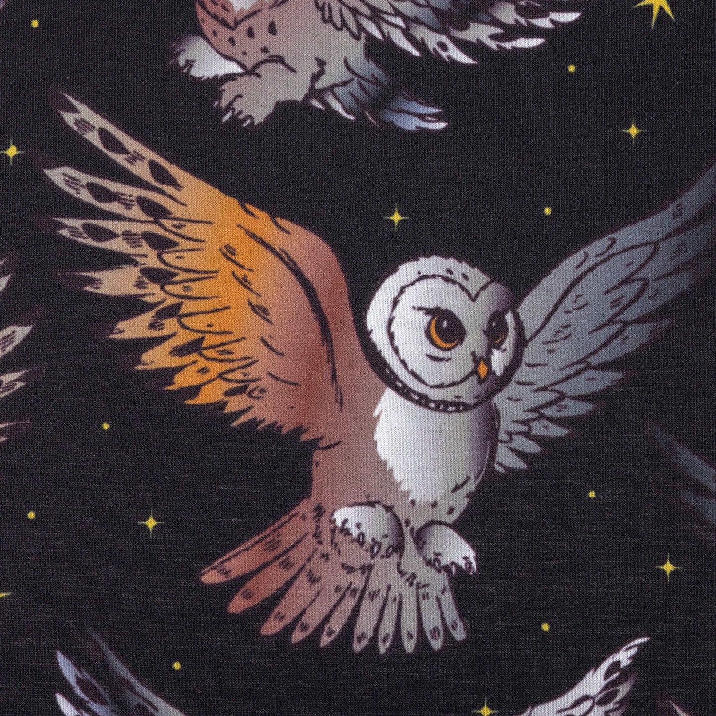 A close up look at the What a hoot stretch jersey fabric featuring barn owls in flight with black background and yellow twinkly stars