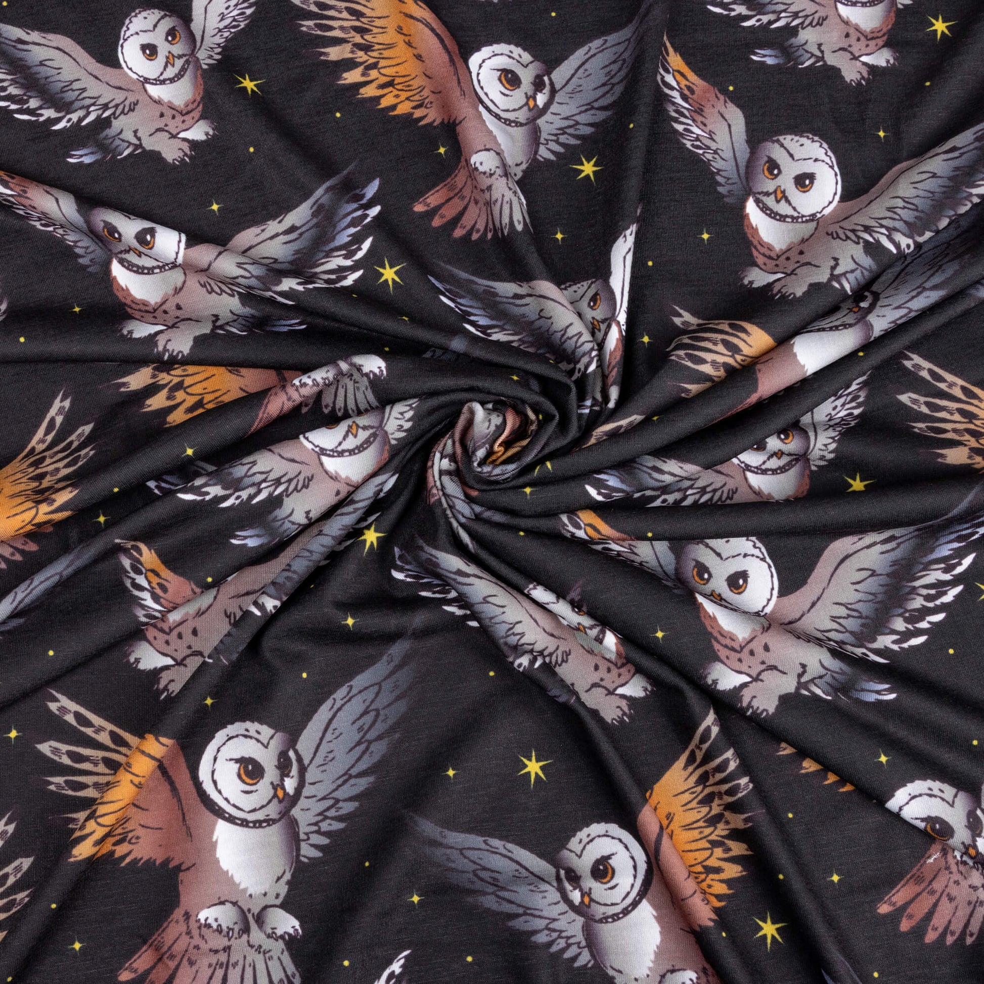 A swirl of the What a hoot stretch jersey fabric featuring barn owls in flight with black background and yellow twinkly stars