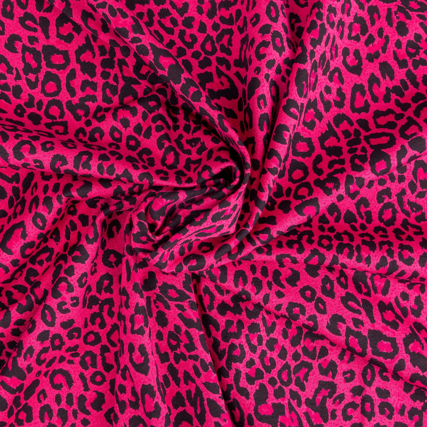 A twirl of bright pink and black leopard print fabric in a soft jersey t-shirt weight perfect for crafting