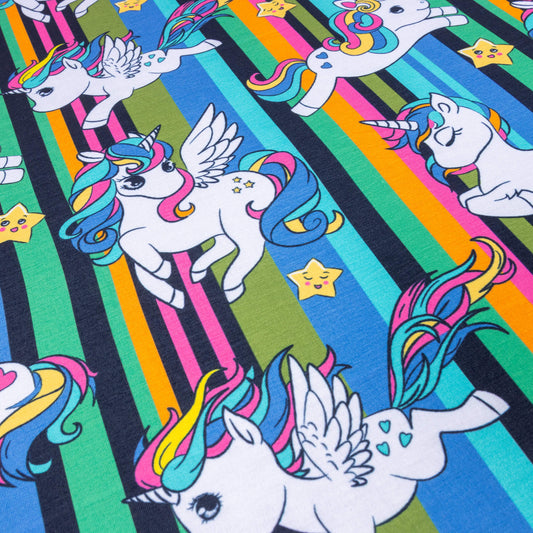 A look at Jersey fabric featuring unicorns and flying unicorns with pink, blue and yellow flowing hair against a background of pink, blue, yellow, green and black stripes. There are also cute smiley stars 